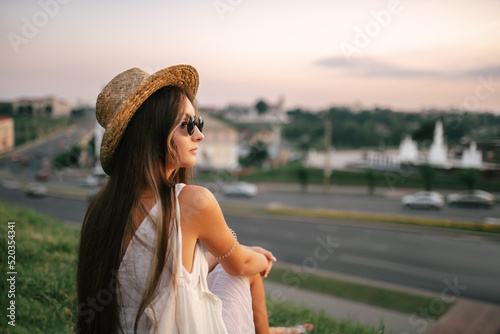 Portrait of a relaxed woman with hat looking forward at the horizon cityscape in the background copy space