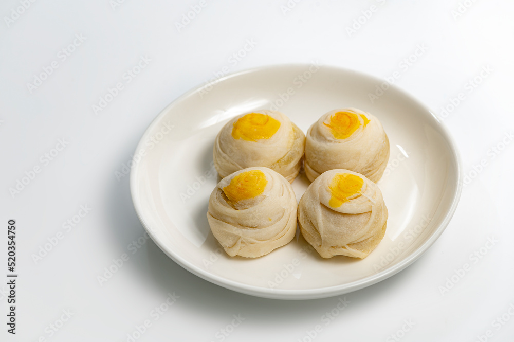 Chinese pastry puff, Beans cake with salted egg yolk lay on white plate on a white background Chinese pastry puff, Beans cake with salted egg yolk lay on white plate on a white background