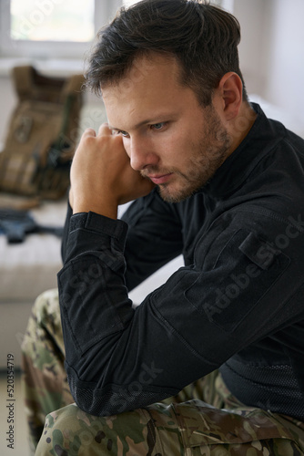 Upset military man sitting at home in thoughts