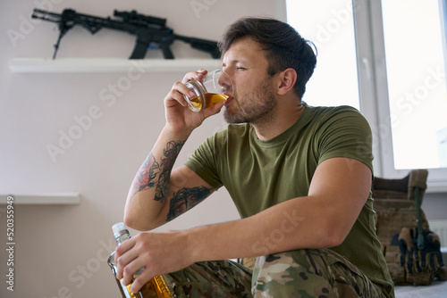 Male combatant making a sip of whisky from glass photo