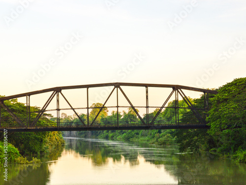 black steel bridge structure in the middle of a rushing river