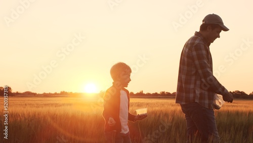 Farmer and his son in front of a sunset agricultural landscape. Man and a boy in a countryside field. Fatherhood  country life  farming and country lifestyle.