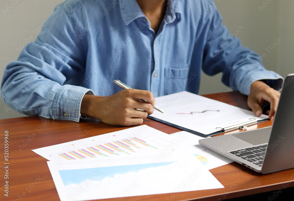 Businessman using laptop to analyze graphs and charts on his desk. Successful work planning Businessman using laptop to analyze graphs and charts on his desk. Successful work planning