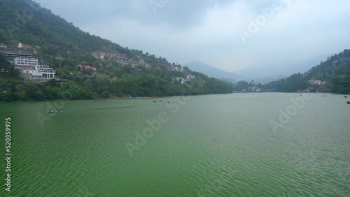 hyper time lapse shot showing boats moving rapdily across the green waters of nainital bhimtal naukuchiatal lake nestled between hills with fog in the distance showing this tourist paradise photo