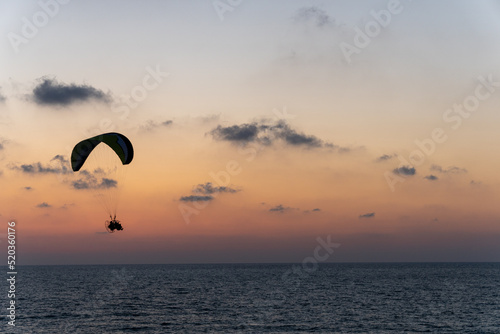 Men fly on parachute at sunshine