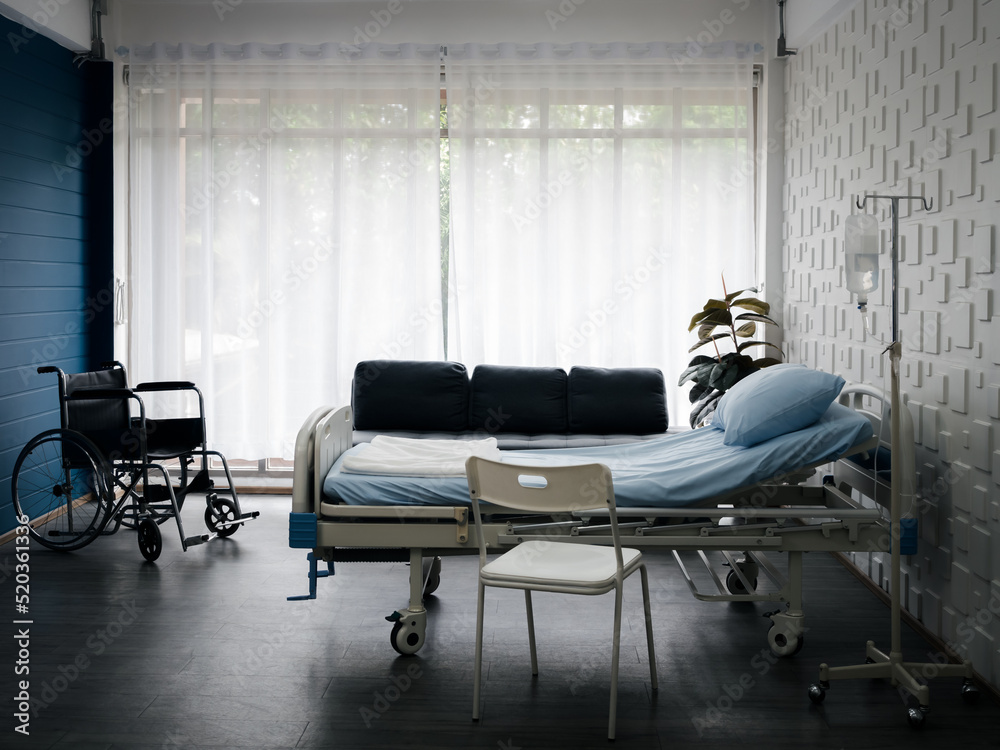 Empty electric adjustable patient bed in a hospital room with chair