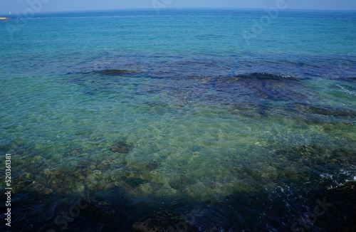 Clear sea water surface, stones and glare