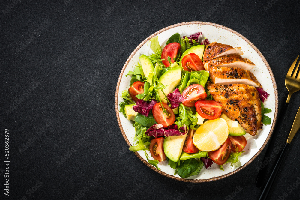 Healthy food concept. Grilled chicken with fresh salad at black background. Top view with copy space.