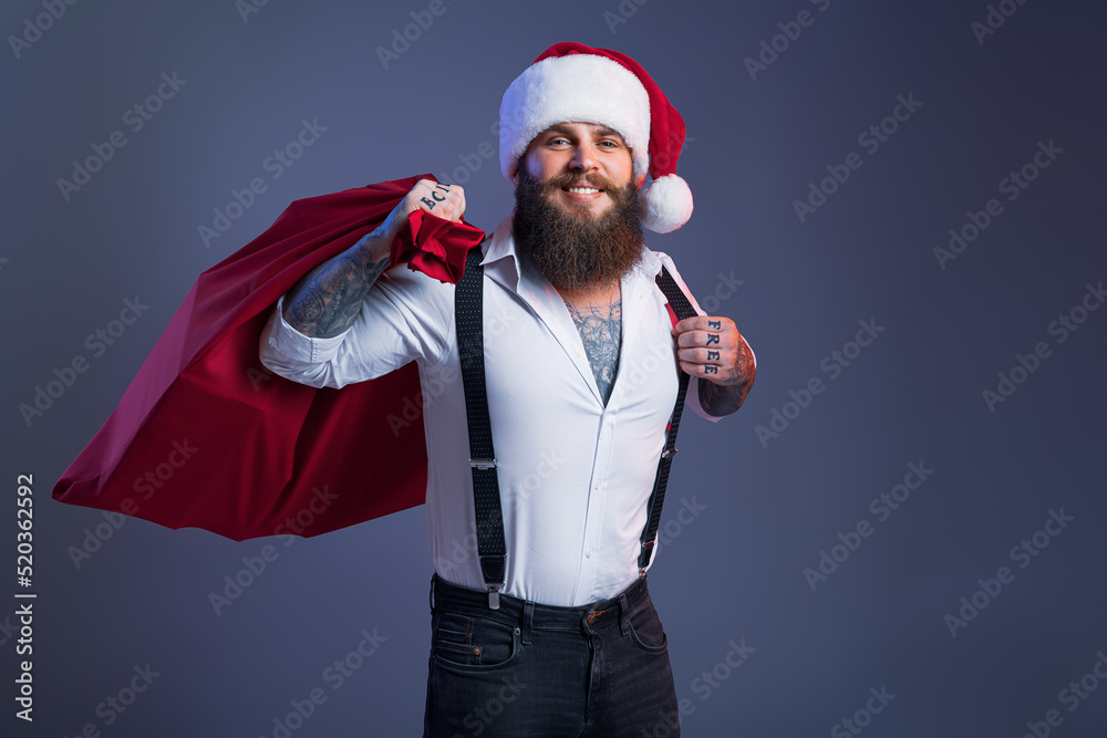 Happy bearded man in Santa's hat holds big sack with presents. Christmas sales. New Year concept