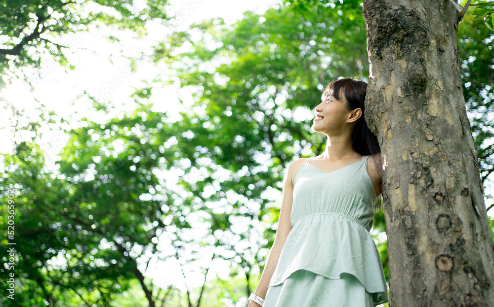 Beautiful young woman relaxing at park during summer season with closed eyes. Happy free natural girl breathing deeply in park with foliage in background. Pretty woman expressing freedom outdoor. Beautiful young woman relaxing at park during summer season with closed eyes. Happy free natural girl breathing deeply in park with foliage in background. Pretty woman expressing freedom outdoor.