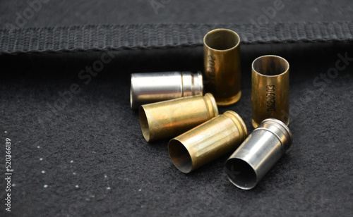 Group of 9mm bullet shells on black leather floor background, soft and selective focus.