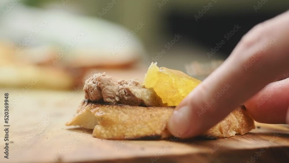 The cook spreading chicken liver pate with apricot and wine gelee on toasted bread.

