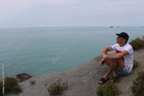 a man in summer sits and looks at the sea