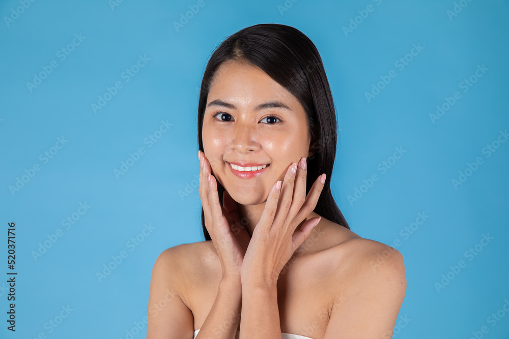 Smiling Asian woman touching healthy skin portrait. Beautiful happy girl model with fresh glowing hydrated facial skin and natural makeup on blue background at studio, Asian Skin care concept. Smiling Asian woman touching healthy skin portrait. Beautiful happy girl model with fresh glowing hydrated facial skin and natural makeup on blue background at studio, Asian Skin care concept.
