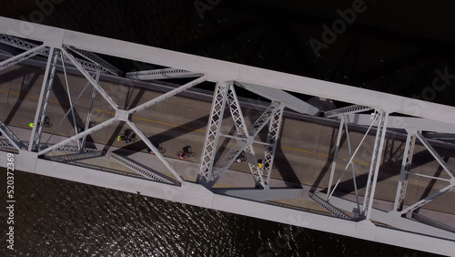 Group of cyclists pedaling on Barra de Santa Lucia old Bridge in Uruguay. Aerial top down