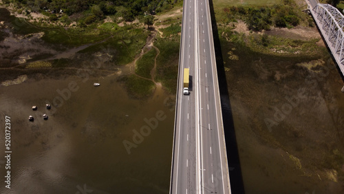 Aerial shot of yellow truck driving on Barra de Santa Lucia Bridge during sunny day in Uruguay photo