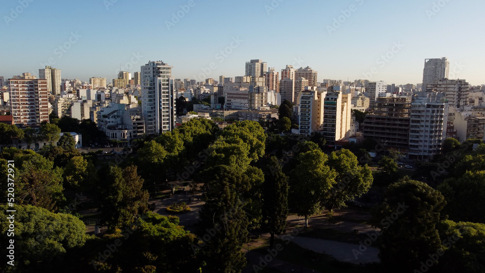 Drone shot of idyllic Centenario Park surrounded by giant skyscraper city of Buenos Aires during sunset