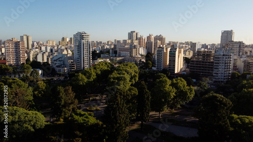 Drone shot of idyllic Centenario Park surrounded by giant skyscraper city of Buenos Aires during sunset