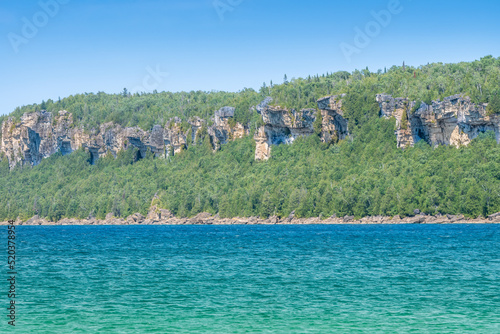 Amazing clean fresh water and green spruce forest on rocks at Lion's Head Beach Harbour in Lion's Head Provincial Park Ontario Canada. Isthmus Bay lake Huron. Great place for vacation tourist visit.