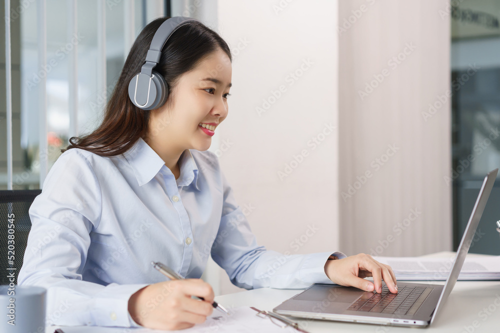 Business concept, Businesswoman in headset to meeting on video conference and taking notes on paper Business concept, Businesswoman in headset to meeting on video conference and taking notes on paper