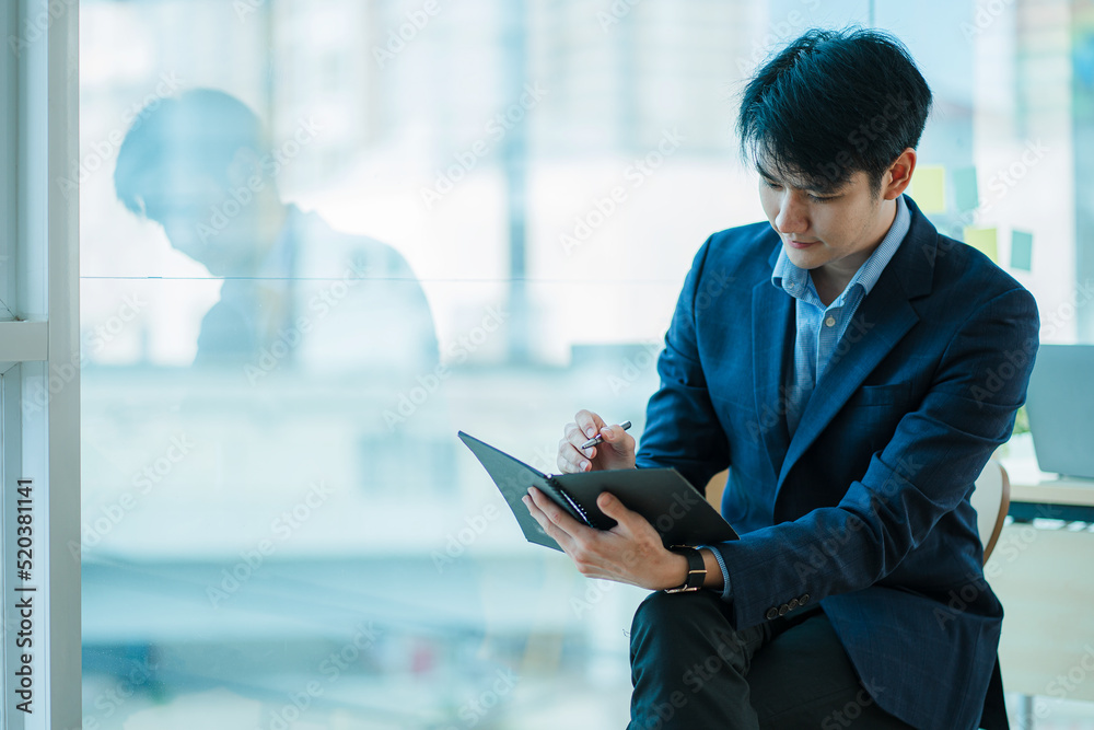 Handsome young Asian businessman sitting alone in the office Handsome young Asian businessman sitting alone in the office