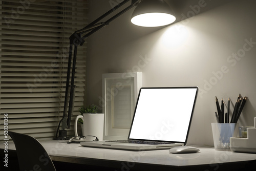 Home office desk with laptop, picture frame and stationery. Empty screen for your advertise text.