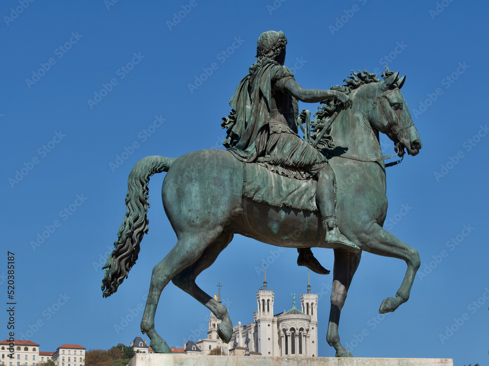 Obraz premium Statue of King Louis the 14th and in the background the Fourvière hill on which the Notre Dame de Fourvière basilica is placed in Lyon France