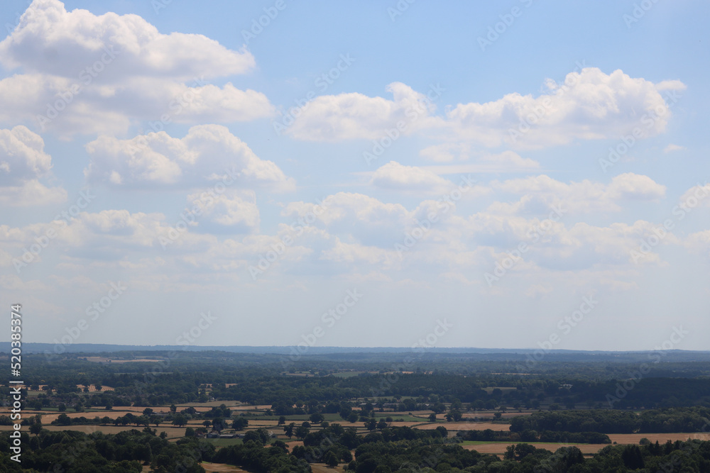 English countryside with field in foreground and blue sky with copy space