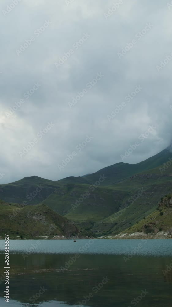 Russia, Caucasus. A lone rowboat sails on lake among the mountains Russia, Caucasus. A lone rowboat sails on lake among the mountains