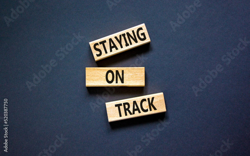Staying on track symbol. Concept words Staying on track on wooden blocks on a beautiful black table black background. Business, motivational and staying on track concept. Copy space.