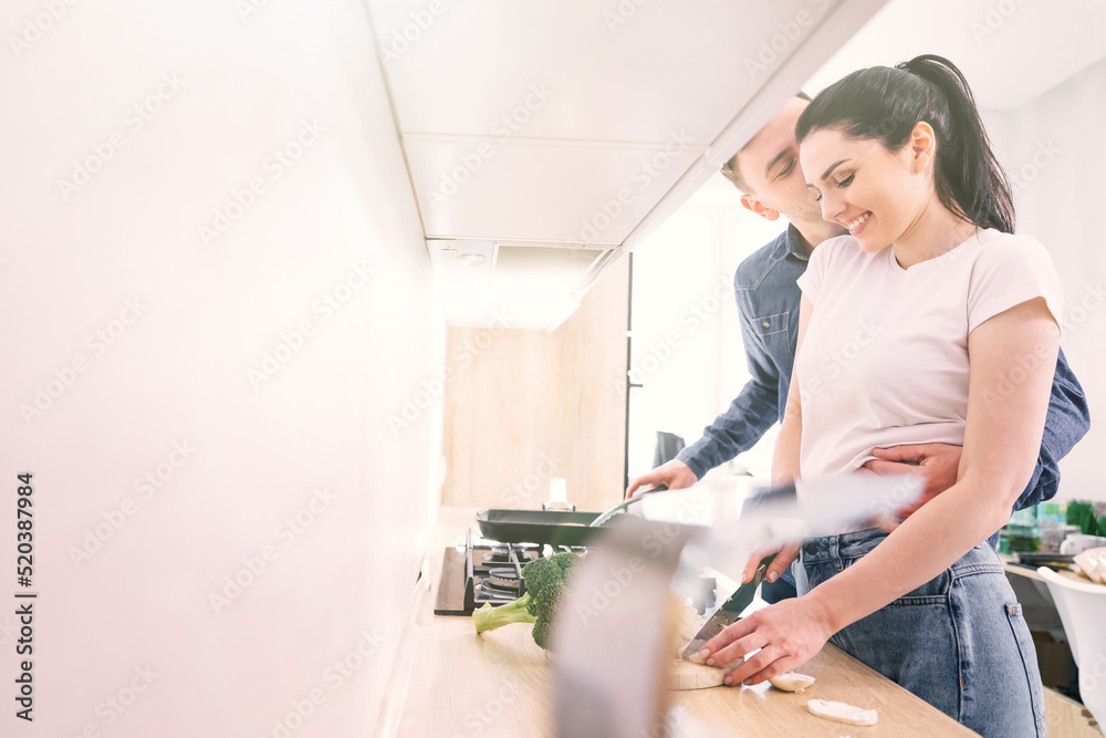 cute couple hugging in the kitchen while cooking steak for dinne cute couple hugging in the kitchen while cooking steak for dinne