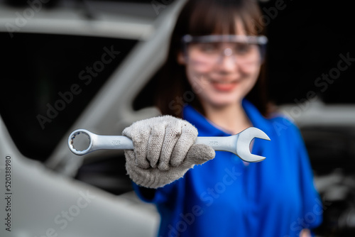 Close-up photo of technician or auto repair. Woman repairman holding metal wrench in garage. Auto repair service concept. Car prototype concept. maintenance technician