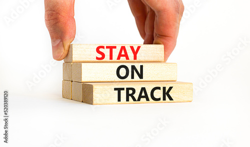 Stay on track symbol. Concept words Stay on track on wooden blocks on a beautiful white table white background. Businessman hand. Business, motivational and stay on track concept. Copy space.