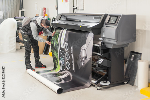 Technician operator works on large premium industrial printer plotter machine photo