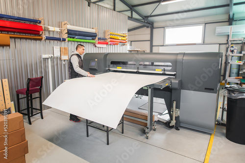 Technician operator works on large premium industrial printer plotter machine photo