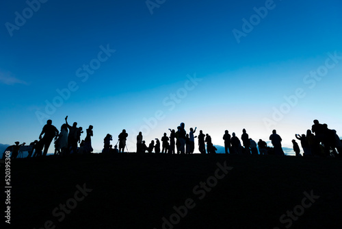 Silhouettes of tourist crowd waiting for the sunrise and doing activity  taking a photo  selfie with nature on the hill at viewpoint