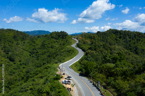Aerial view of country asphalt road in forest. Drone flying over curved country road in the mountain. © PPstock