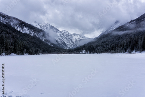Winter landscape with frozen lake, sorrounded rocky mountains covered in the fog. After season, Jagersee, Salzburger Alps, Austria, Europe.