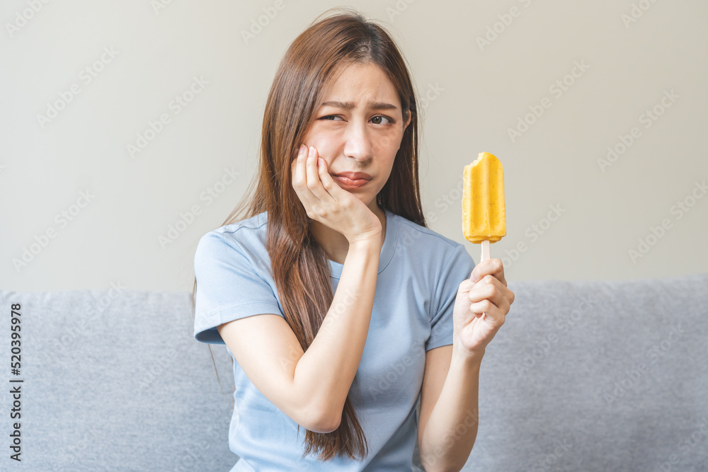 Face expression suffering from sensitive teeth and cold, asian young woman, girl feeling hurt, pain eating ice cream, lolly. Toothache molar tooth at home, dental problem isolated on white background. Face expression suffering from sensitive teeth and cold, asian young woman, girl feeling hurt, pain eating ice cream, lolly. Toothache molar tooth at home, dental problem isolated on white background.