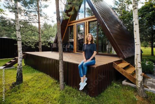 Woman in a summer house sitting on terrace and enjoys beautiful view and fresh air photo