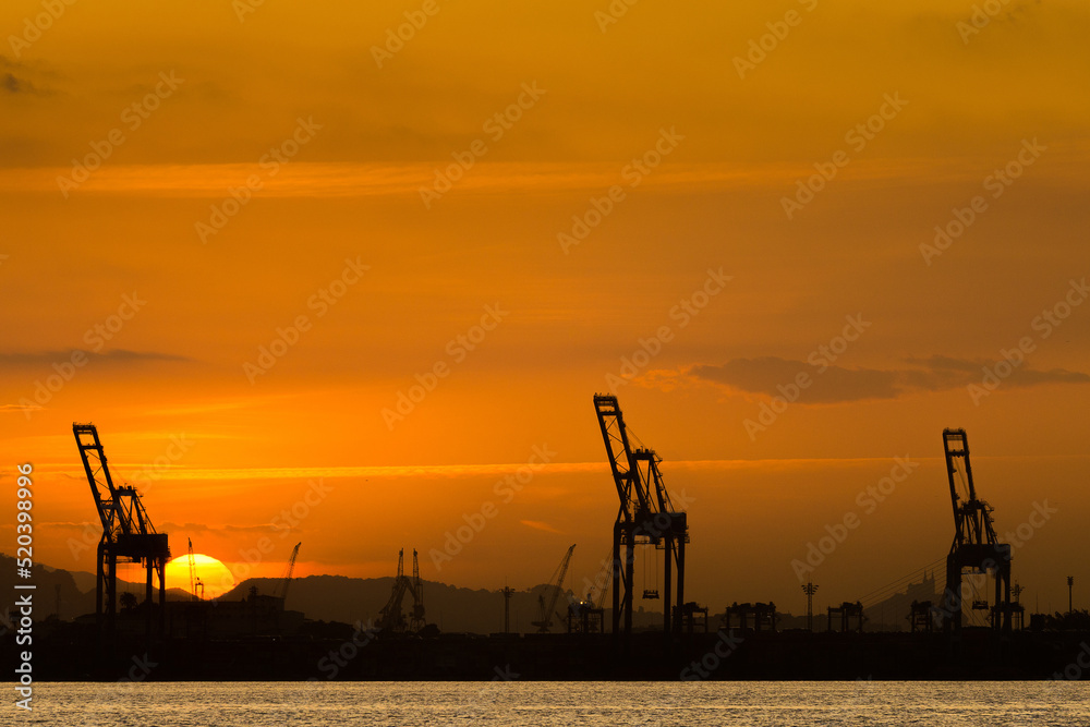 Industrial Cranes in the Horizon With Sun Setting Behind