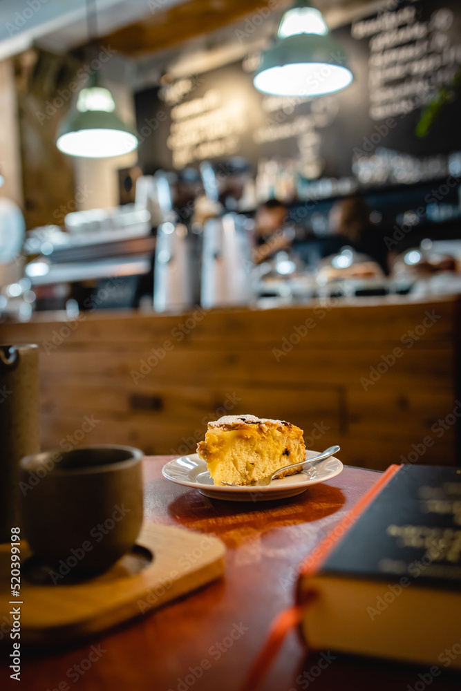 Vertical closeup shot of the peach cake in a loft cafe with coffee and book on the side Vertical closeup shot of the peach cake in a loft cafe with coffee and book on the side