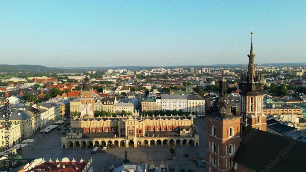 Aerial drone view of Krakow main market square, clock tower, St. Mary's church and people walking around in sun rise. Krakow, Poland. Aerial drone view of Krakow main market square, clock tower, St. Mary's church and people walking around in sun rise. Krakow, Poland.