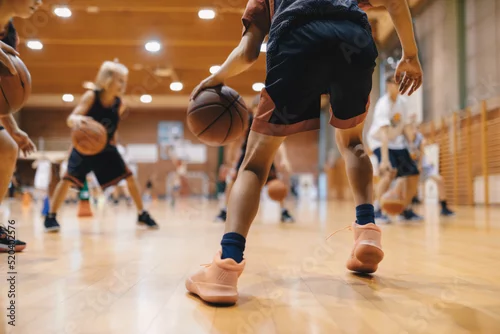 Obraz Junior level basketball player bouncing basketball. Young basketball player with classic ball. Basketball training session for youth. School sports class