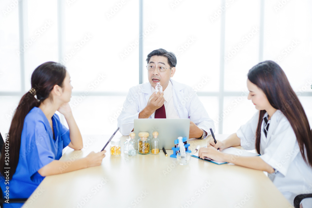 Senior and young doctor discussing about vaccine or medicine at hospital. Group of doctors and nurse talking about treatment and take notes in beautiful office room. Senior and young doctor discussing about vaccine or medicine at hospital. Group of doctors and nurse talking about treatment and take notes in beautiful office room.