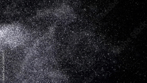 Abstract animation of small white particles exploding isolated on black background. Animation. White dry inks dust flying into the sides in the dark.