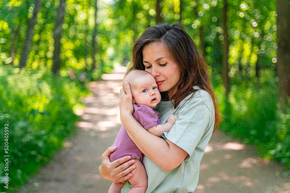 A young mother walks in a summer park with her cute baby kid A young mother walks in a summer park with her cute baby kid