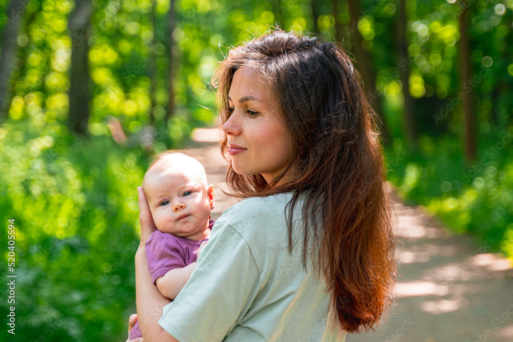 A young mother walks in a summer park with her cute baby kid A young mother walks in a summer park with her cute baby kid