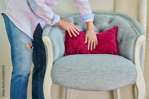 A woman decorating blue armchair with velvet pink cushion