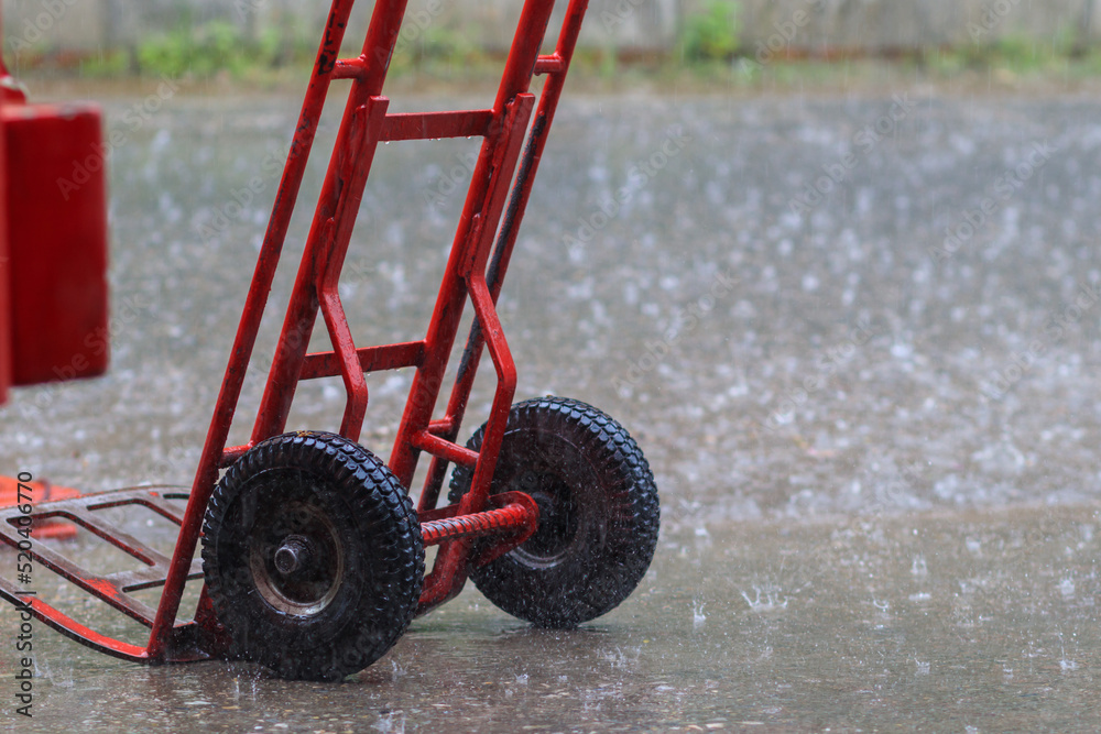 red cart was parked in the rain because it was prepared to transport goods to the convenience store, but when there was a heavy rain storm causing the goods to be halted and the cart left in the rain.